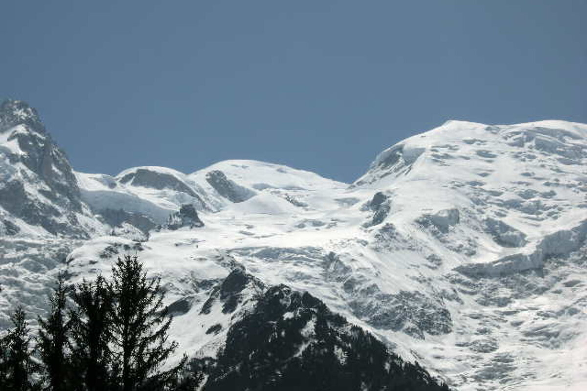 A snowy mountain with a blue sky in the background
