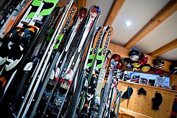 an image of a lot of skis and helmets in a ski rental shop