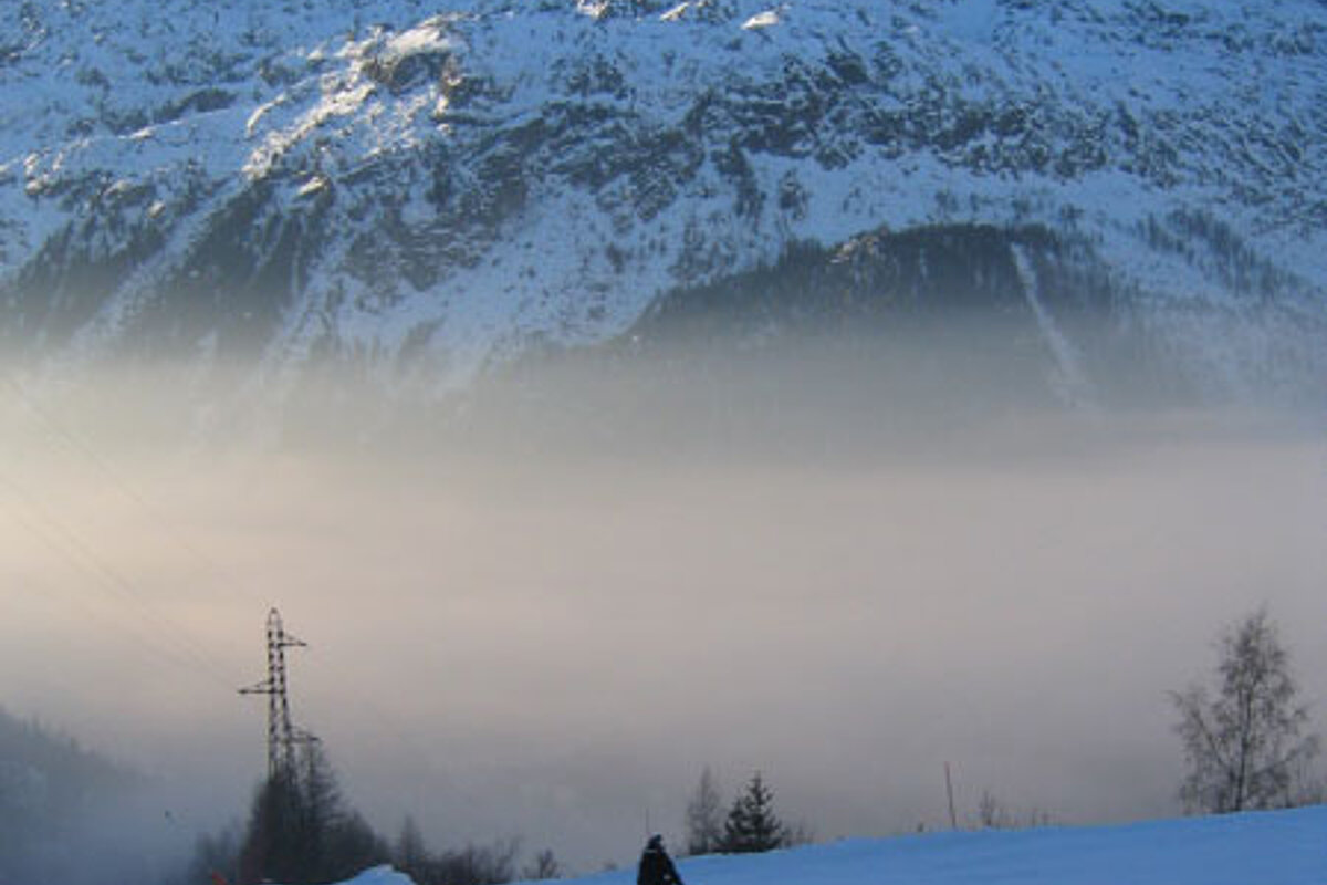A person skiing down a snow covered slope with mountains in the background