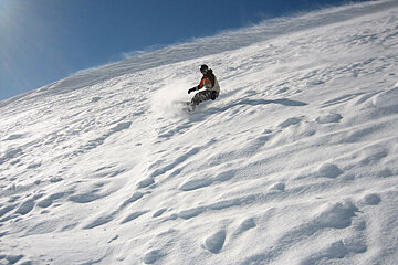 A person riding a snowboard down a snowy hill