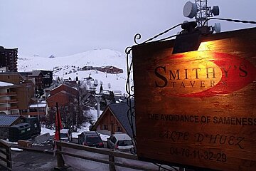 A sign for smith 's tavern is lit up in the snow