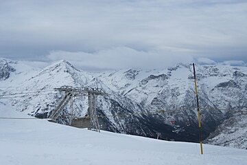 Grey clouds over snow covered mountains and chair lift