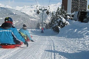 A group of people are sledding down a snow covered slope