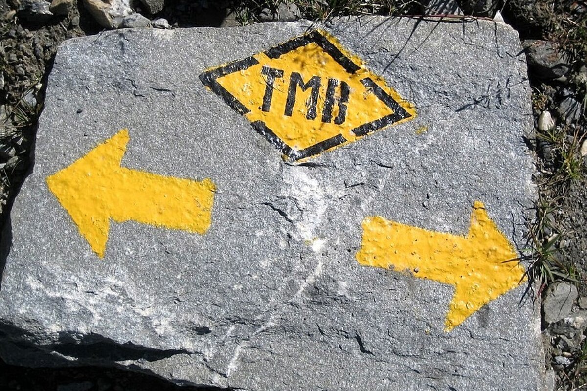 A yellow sign on a rock that says tmb