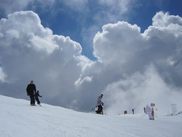 People skiing down a snow covered slope with a sign that says ' ski ' on it