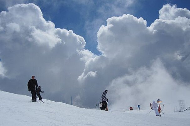 People skiing down a snow covered slope with a sign that says ' ski ' on it