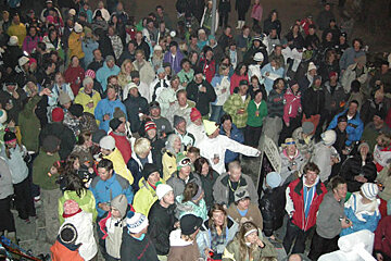 A large group of people are gathered in a crowd with one man wearing a jacket that says ' salomon ' on it