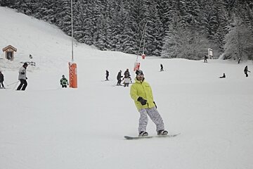 Boarder on piste wtih a few skiers behind