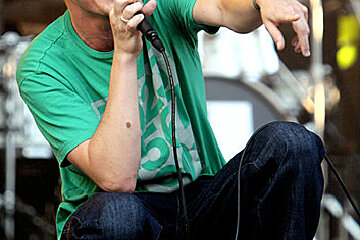 A man in a green shirt is singing into a microphone