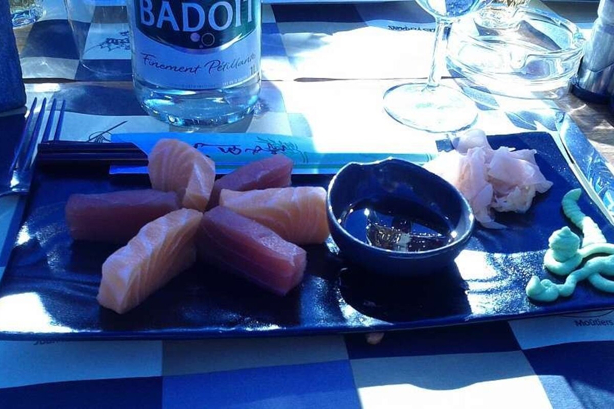 A bottle of badoit sits on a table next to a plate of food