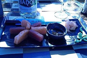 A bottle of badoit sits on a table next to a plate of food