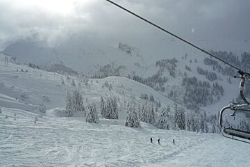 Skiers are going down a snow covered slope with a chair that says ' salomon ' on it