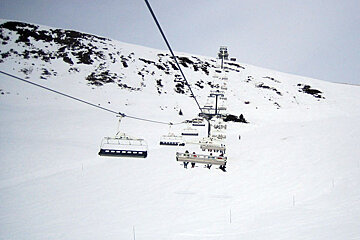 A ski lift is going up a snow covered mountain