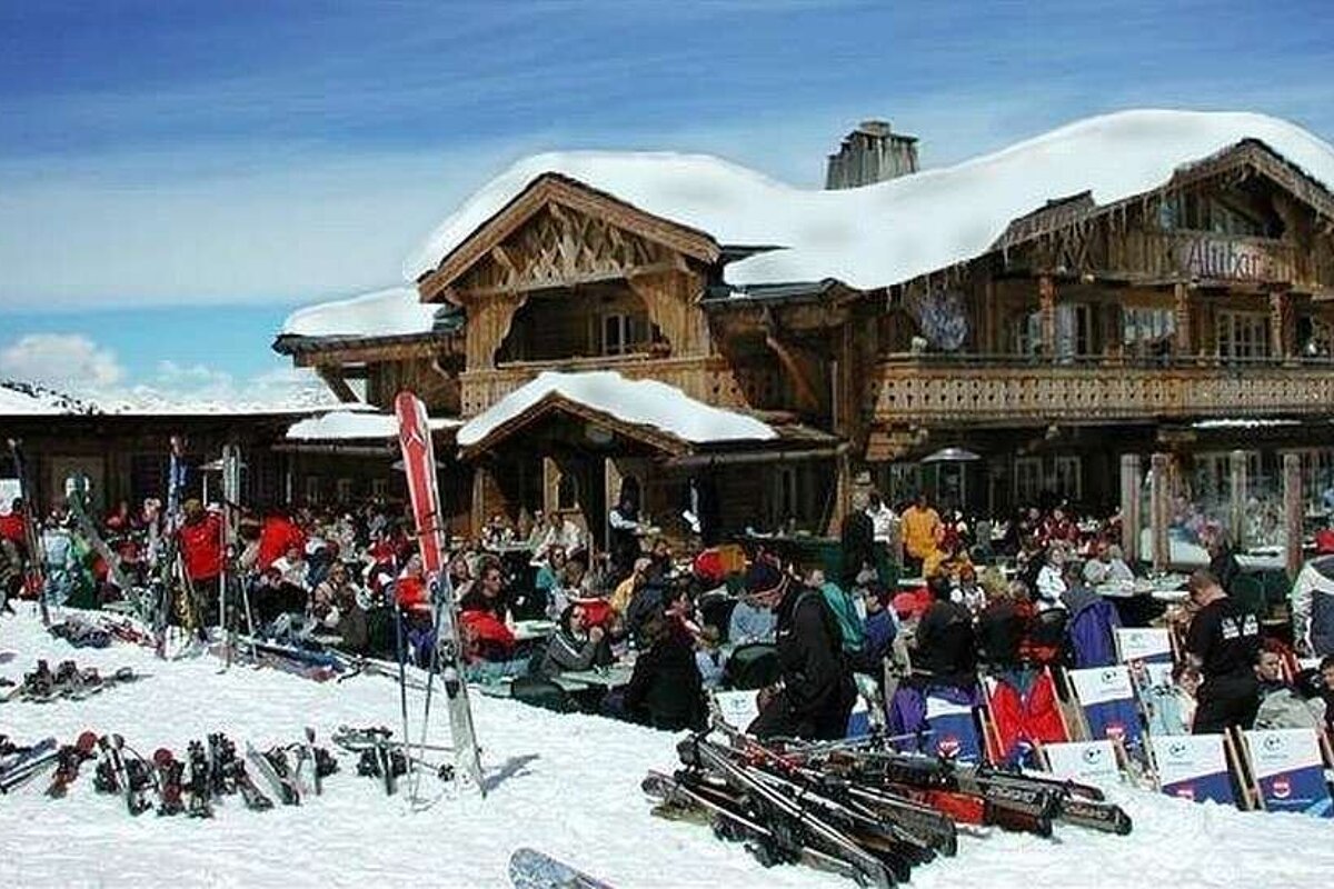 A group of people are sitting outside of a snow covered building