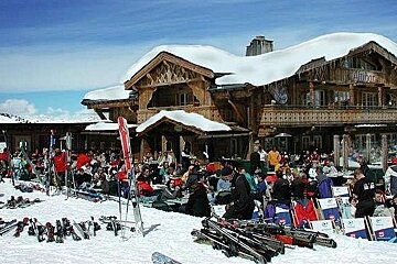 A group of people are sitting outside of a snow covered building