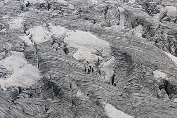 An aerial view of a group of people walking on a glacier
