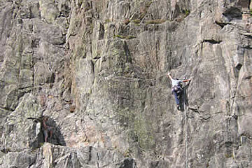 A man and a woman are climbing up a rock wall