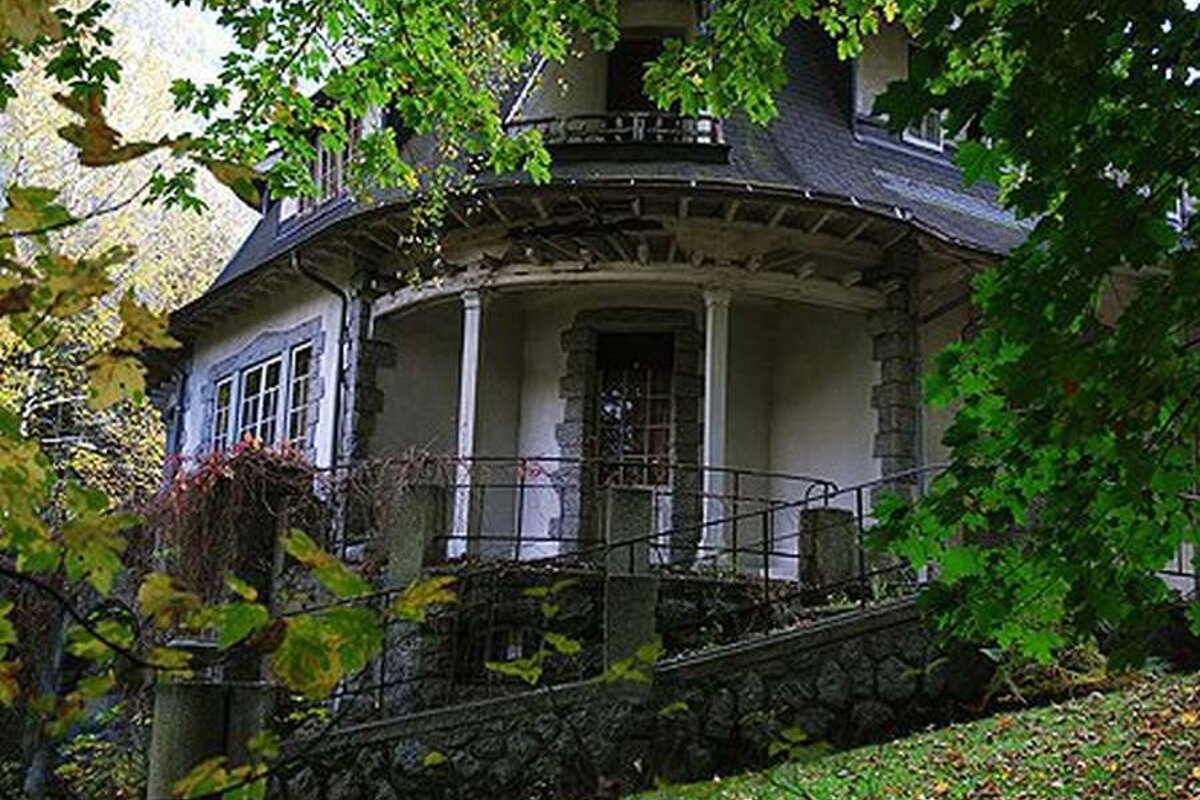 A house with a circular porch is surrounded by trees