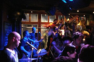 A crowd of people are watching a band perform in a dark room