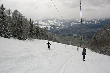 People skiing down a snowy slope with mountains in the background