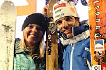 A man and a woman standing next to each other holding skis that say north face on them