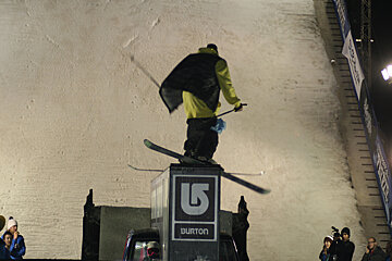 A snowboarder is doing a trick on top of a burton sign