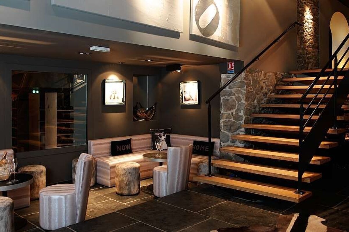 an image of some wooden stairs with bar stools and stone walls