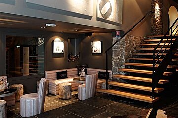 an image of some wooden stairs with bar stools and stone walls