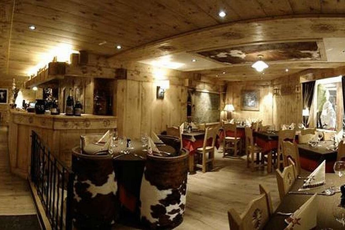 an image of a restaurant with cow hide and wooden chairs on a wooden floor