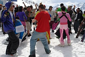 A group of people are dancing in the snow near a sign that says ' altitude ' on it