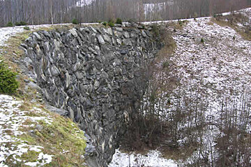 A large rock formation in the middle of a snowy field