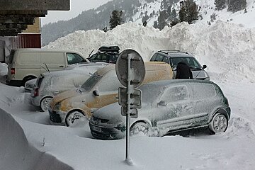 Cars parked with huge mound of snow behind them