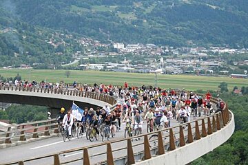 A large group of people are riding bicycles on a bridge