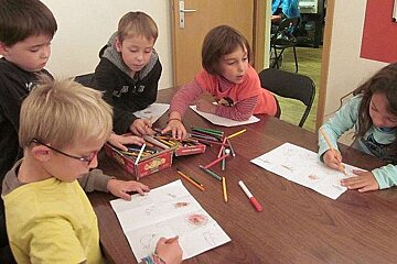 an image of a group of children sat round a table drawing