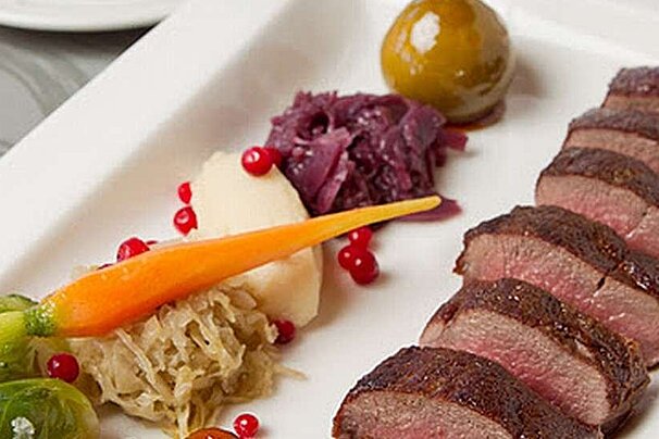 an image of sliced meat on a plate with a carrot and other vegetables