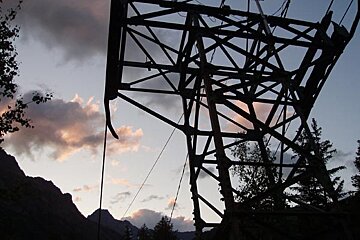 A very tall metal structure is silhouetted against a cloudy sky