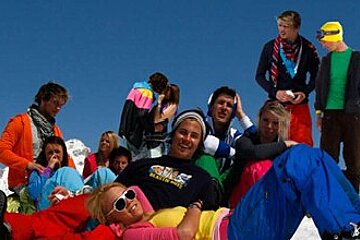 A group of people are laying on top of a snow covered mountain
