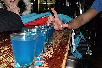 A row of shot glasses with blue liquid in them