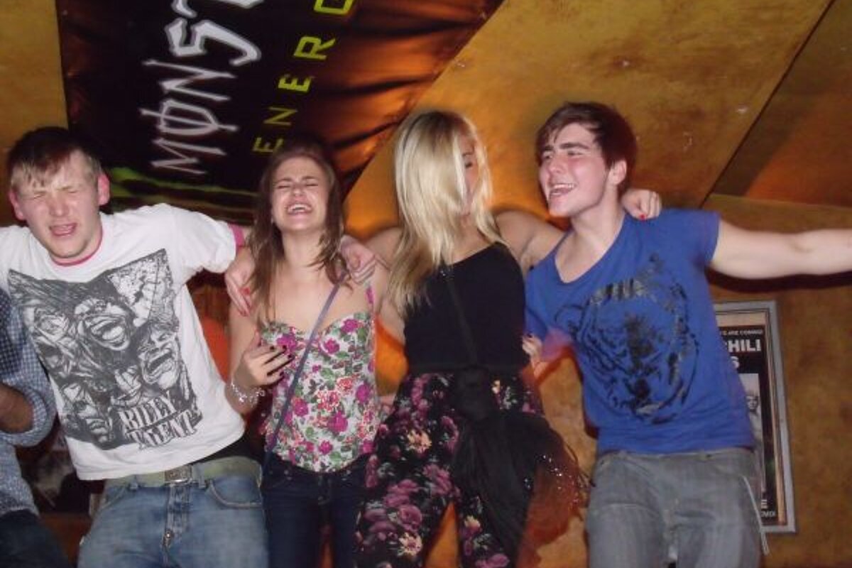 A group of people posing in front of a monster energy sign