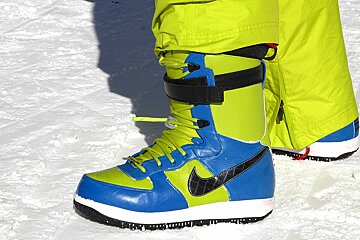 A person wearing a pair of blue and green nike boots
