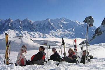 A group of people are sitting in the snow with skis