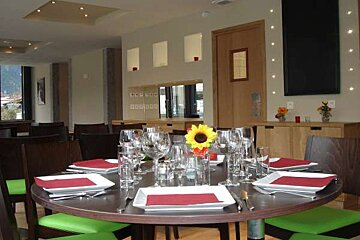 A round table with plates , glasses , and a sunflower on it in a restaurant