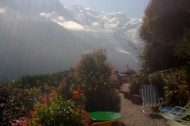 A green table and chairs in front of a mountain