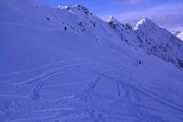 A person skiing down a snowy mountain with a blue sky in the background