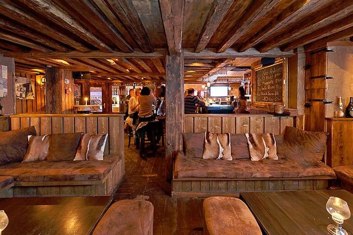 an image of a room with seating covered in hide cushions and large beams in the roof