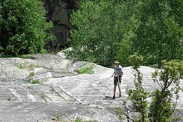 A man is standing on a rock holding a rope