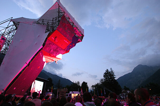 A man climbs a climbing wall in front of a crowd
