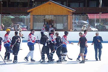 A group of hockey players on a rink with a restaurant pizzeria in the background