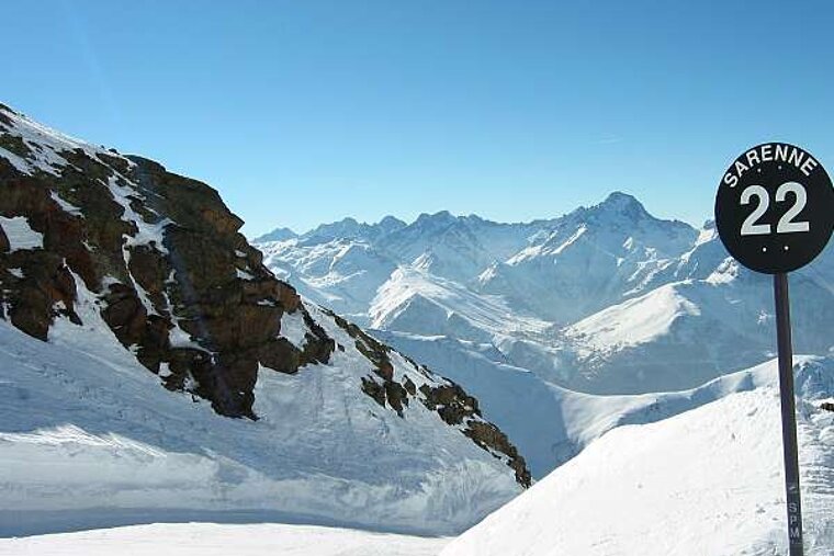 A black sign with the number 22 on it is sitting on top of a snow covered mountain