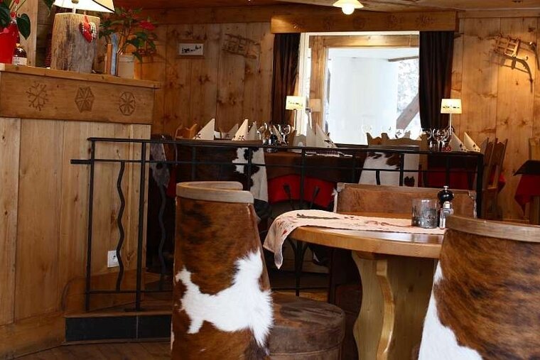 an image of a corner in a restaurant with tall stools wrapped in cow hide